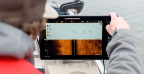 A person on a boat looking at a tablet screen that shows the location of crab pots.