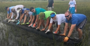 A group of people moving a large wooden piling.