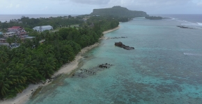 Three derelict vessels partially submerged close to a beach.