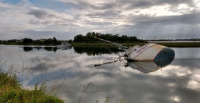 A derelict vessel on its side and partially submerged in the water.