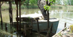 Derelict vessel in waterway being removed by heavy equipment.