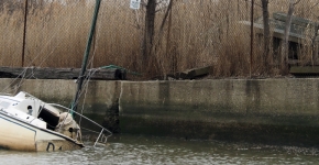 A partially sunken vessel near the water's edge.