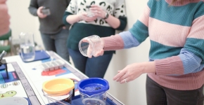 Workshop participants at a table pouring containers of water through a filter that traps debris in the water.