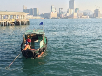 People remove marine debris floating in Hong Kong with nets.