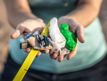 Person holding plastic debris, on a beach.