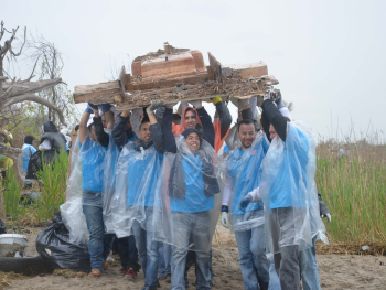 Workers lift heavy debris from beach.