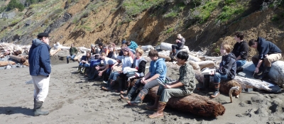 On a beach, a man is instructing volunteers.