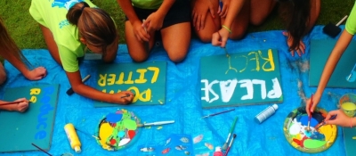 Kids painting signs on a tarp.