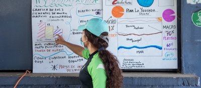 A volunteer graphs the results of marine debris surveys on a wall poster.