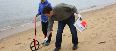 Two people measuring distance on a beach.