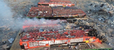 A still smoking pile of firework debris on a beach.