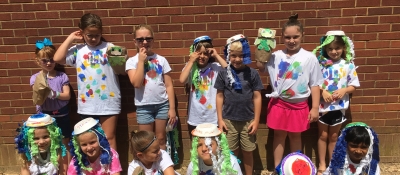 A group of middle school students stand in front of a brick wall.