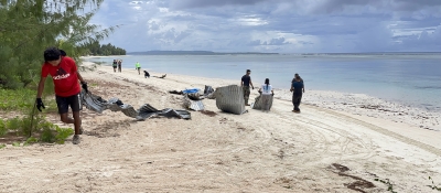A group of volunteers drag damaged metal sheeting along a beach.