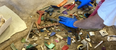 A volunteer with blue gloves sorting through pieces of debris.