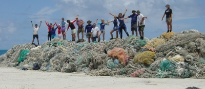 People standing on top of a large pile of derelict nets. (Photo Credit: NOAA)