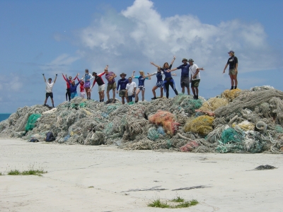 NOAA divers stand on a pile of nets they removed in Hawaii. 