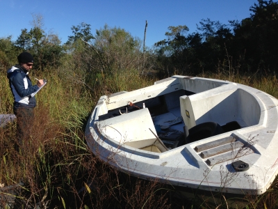 A researcher takes data notes on a vessel in Dog River. 