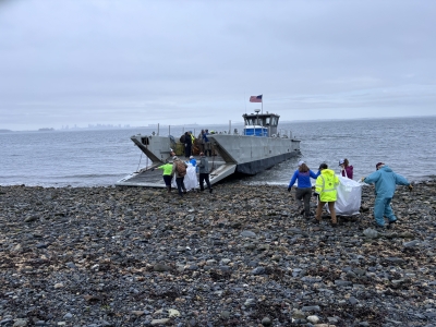 A group of people bringing trash bags full of marine debris on board a vessel during a cleanup.