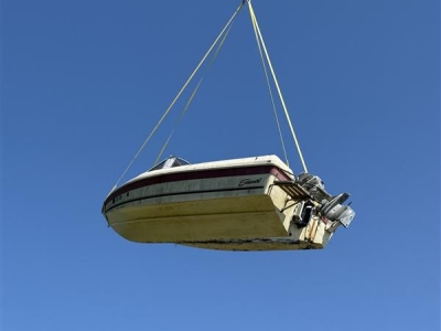 A derelict vessel lifted into the sky by a helicopter.