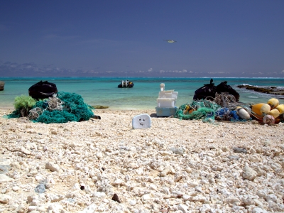 Two piles of marine debris collected from separate 300-m shoreline segments are staged to be loaded onto the small boat. (NOAA PIFSC Coral Reef Ecosystem Program) 