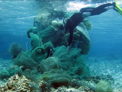 Scuba diver managing a huge wad of derelict fishing net bundled for removal.