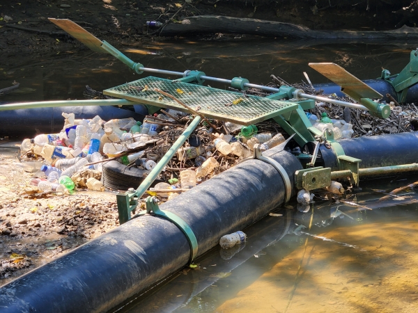 A trash trap device placed in a river that captured plastic water bottles and a tire, preventing the marine debris from moving to other areas.