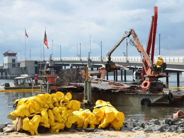 Floats are being utilized to contain random debris, caused by demolition of a home destroyed by Hurricane Sandy, from moving further into Barnegat Bay during the removal process.