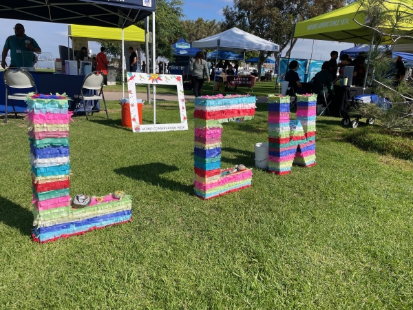 Piñata "LCW" letters placed on a lawn in the middle of a community event. 