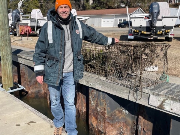 The Director of the NOAA Marine Debris Program posing next to derelict fishing traps.