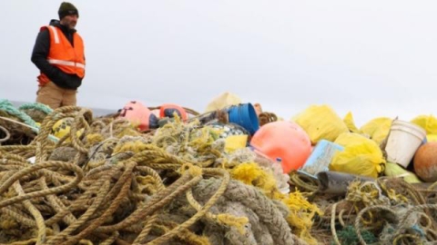 Marine debris from a cleanup in St. Paul Island, Alaska A person overlooking a large pile of marine debris.