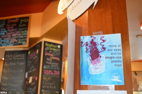 A cafe sign that reads, "Think of our seas and be single-use plastic free!".