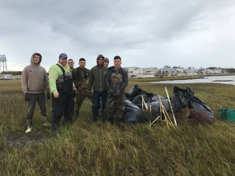 Project participants standing in a marsh alongside bags of collected debris.