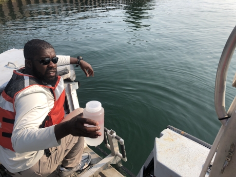 Man collecting water sample from boat.