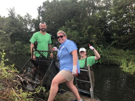 Three project participants pose with a grocery cart found in One Mile Creek.