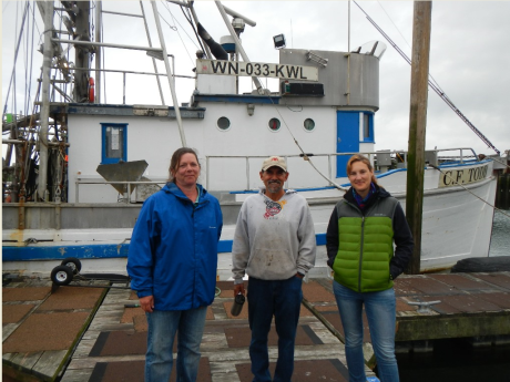 Three people standing in front of a boat.