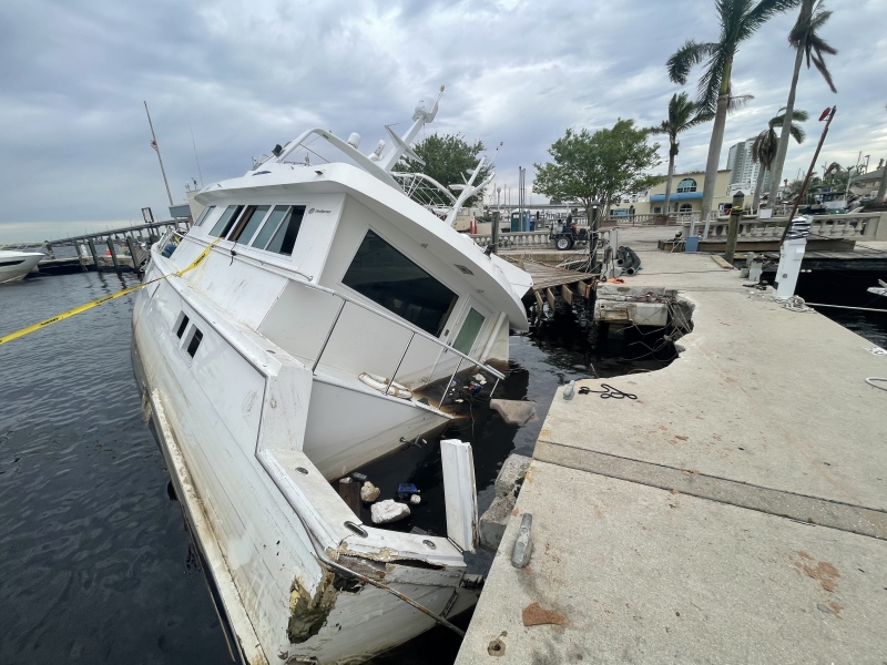 A half sunken derelict vessel that crashed into a marina walkway marked off with caution tape.