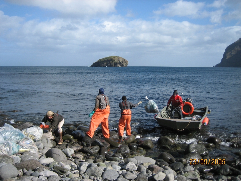 People loading collected debris onto a boat for removal.